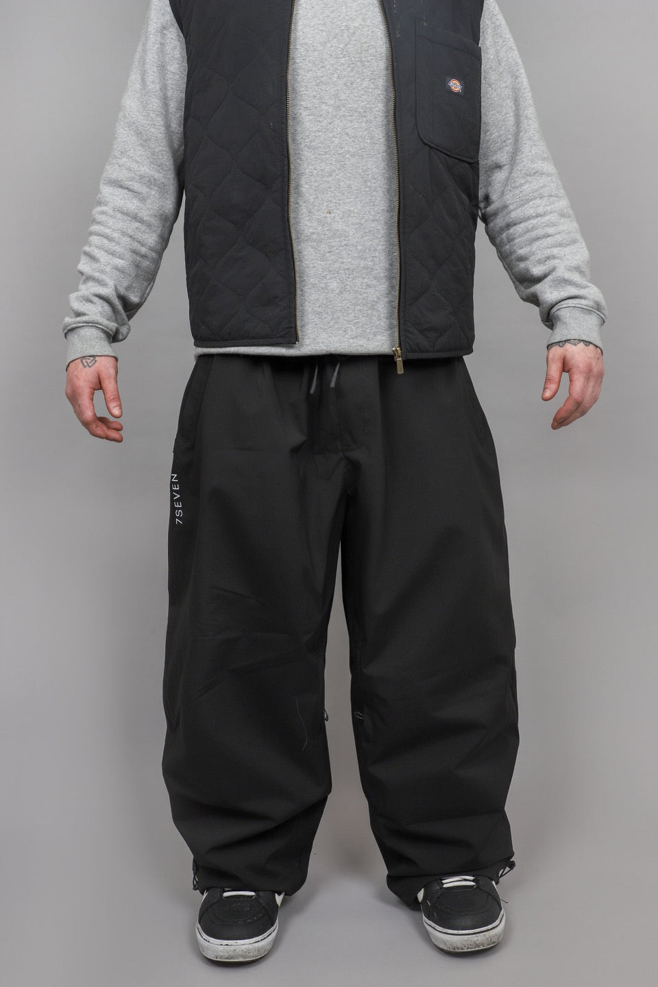 Baggy black snow pants worn with layered clothing