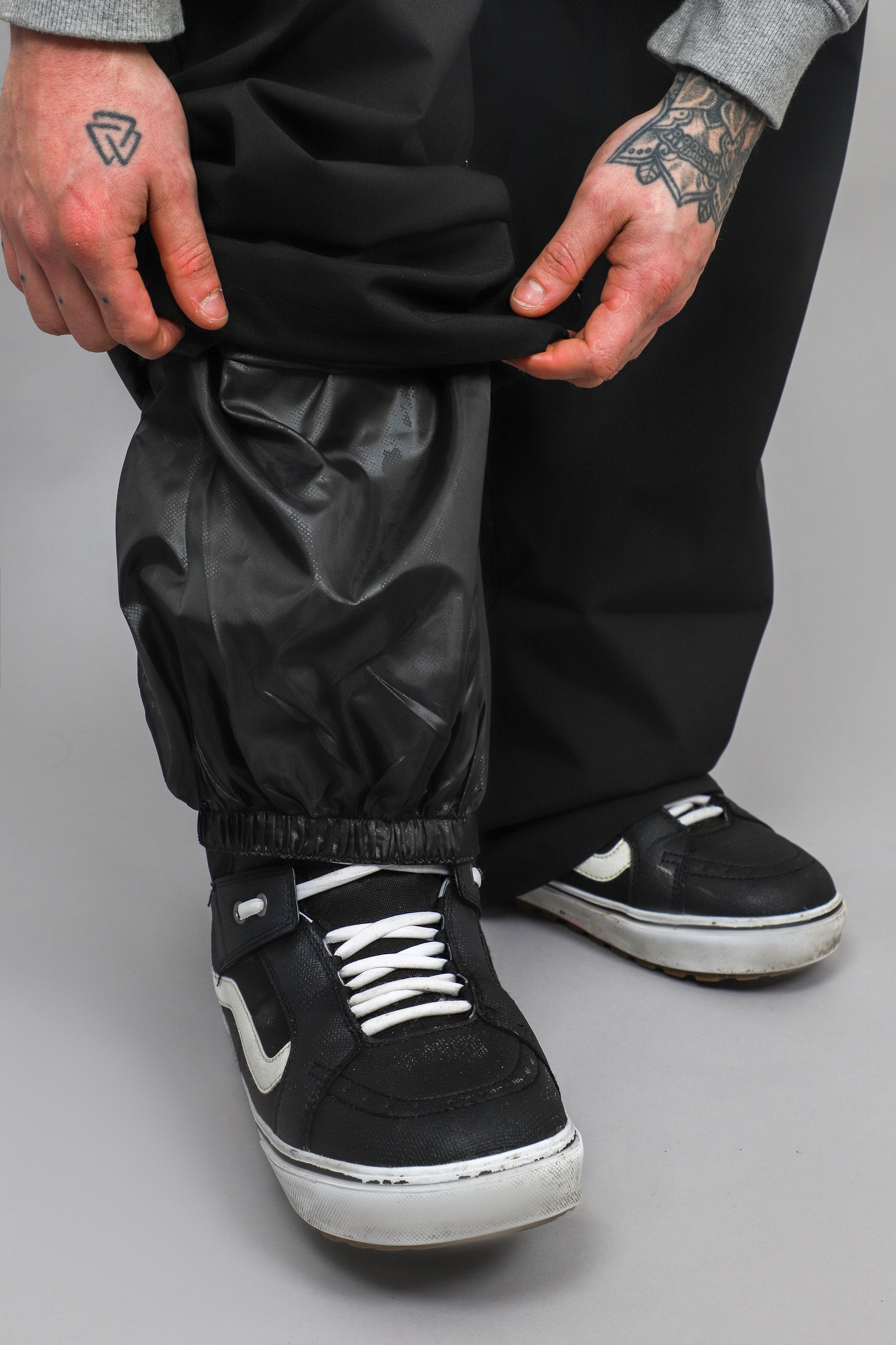 Black Pants cuff lifted to show the internal gaiter around a boot