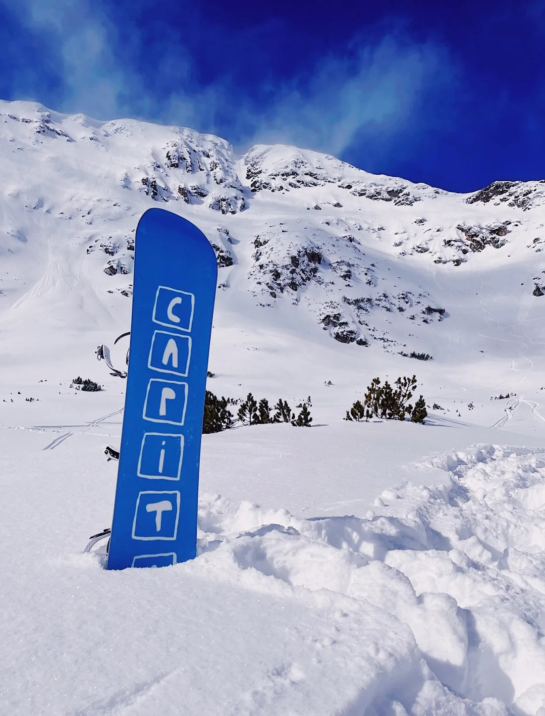 A blue snowboard resting in snow in Bansko