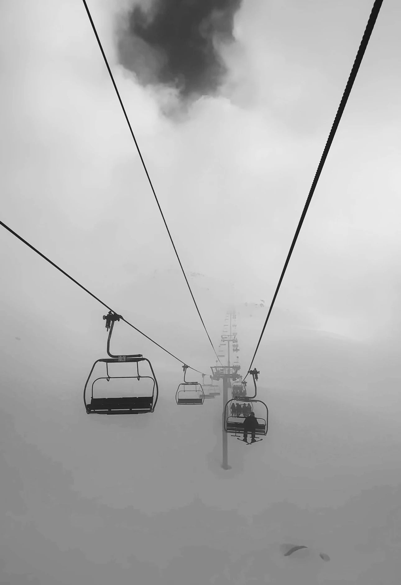 Chairlift disappearing into mountain cloud